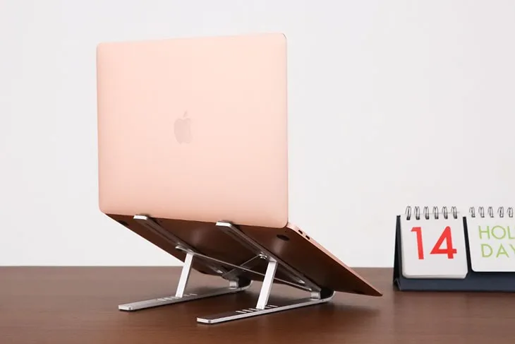 Giá đỡ laptop bằng nhôm màu bạc giúp nâng cao máy, tạo không gian thoáng khí và tăng cường tản nhiệt thụ động, hỗ trợ cách dùng laptop không chai pin hiệu quả
